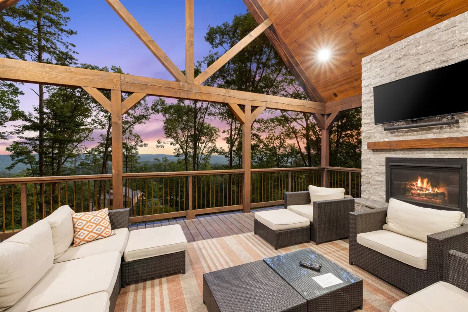 Covered deck lounge with a stone fireplace and the ridge beyond.